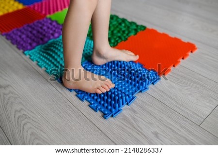The child walks on an orthopedic massage foot mat with different stiffness and texture.Massage effect on the nerve endings of the legs - prevention of flat feet in children.High quality photo