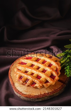 tartlet or tart filled with homemade delicious strawberry jam on a brown wood and cloth for a snack