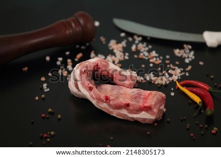 subject photography of a piece of fresh pork meat on a subject table with thawed peppers and decorative salt