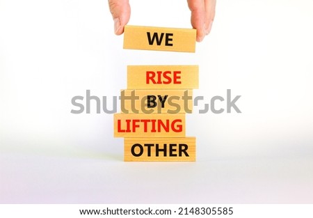 We rise by lifting other symbol. Concept words We rise by lifting other on wooden blocks. Businessman hand. Beautiful white background. Business we rise by lifting other concept. Copy space.