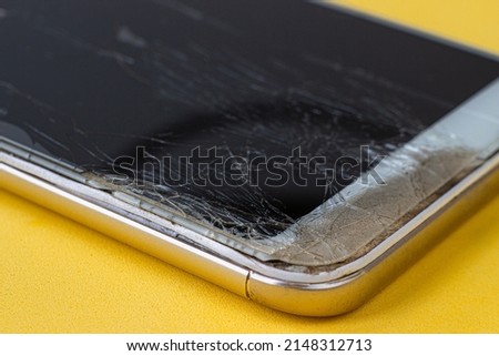 A macro view of a broken screen of a modern smartphone with numerous cracks