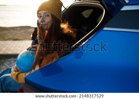 cute casual woman ready for travel with globe in car 