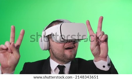 Office worker dances happily with his hands up, he uses virtual reality glasses