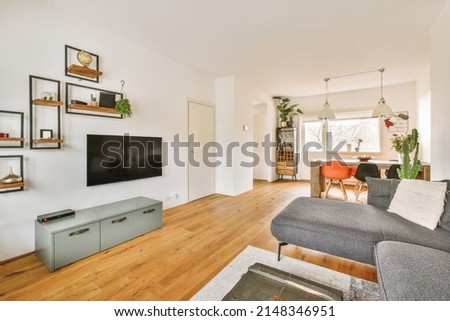 The interior of a cozy living room with a large sofa on a parquet floor and a large bright window in a modern apartment