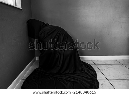 A man sits in a room in a black cloak, hiding from the ghosts. Psychological problems. Soft focus.