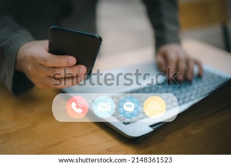 Contact us or the connected customer support hotline. Businessman using laptop and tapping contact icon on virtual screen, phone, email, address, live chat, internet, available 24 hours a day.