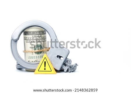 A picture of fake money and handcuff with warning sign on copyspace white background. Warning of money trap concept.