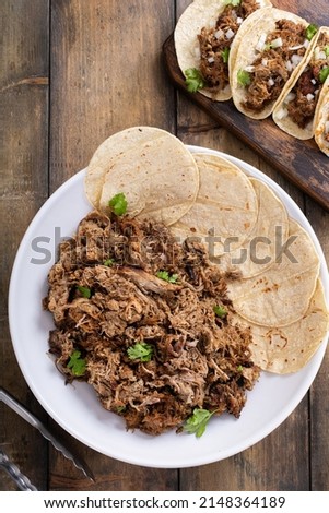 Pork carnitas tacos with onion and cilantro served with soft corn tortillas