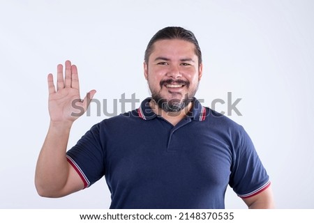 A bearded man in his 30s saying hi or swearing loyalty. Wearing a blue polo shirt. Isolated against a white background.