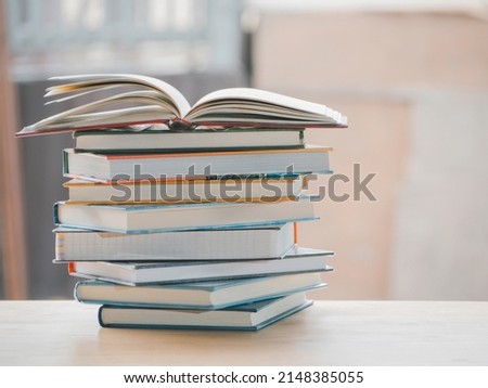 A simple composition of many books, stack or pile of books on wooden table, one of them open with copy space. Royalty-Free Stock Photo #2148385055