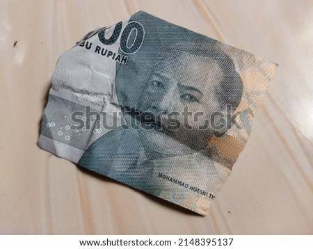 a piece of paper money from Indonesia that has been torn into two thousand rupiah denominations
