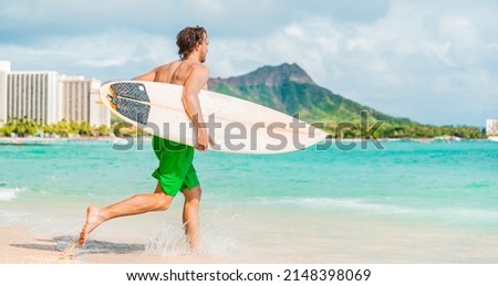 Hawaii surfing lifestyle young man sufer going to surf in blue ocean water in Honolulu, with Diamond Head in background. Oahu island travel vacation Royalty-Free Stock Photo #2148398069
