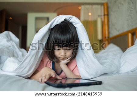 chinese child addicted tablet, kid use telephone, girl watching cartoon on the bed