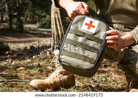 Military army first aid kit. Camouflaged soldier medic. White and red first aid sign. Royalty-Free Stock Photo #2148419173