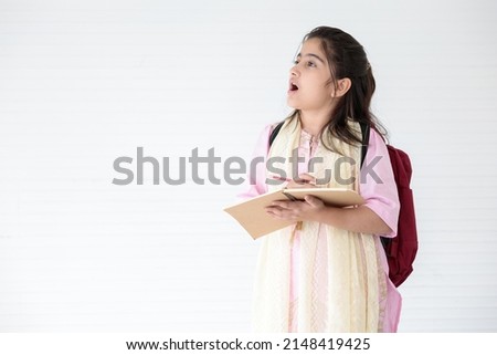 cute Indian girl smiling and writing on notebook for learning, education concept