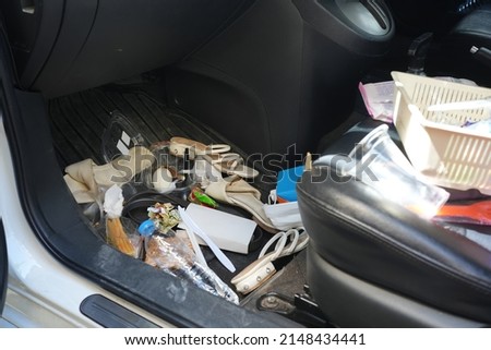 dirty car interior , carpet on the footwell has trash,food waste, dirt spilled across it. Needs to be cleaned and vacuumed inside . car maintenance concept Royalty-Free Stock Photo #2148434441