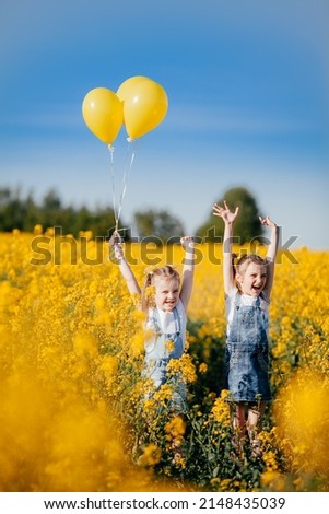 Happy emotions of children who are playing with balls on a yellow field of flowering rapeseed. Royalty-Free Stock Photo #2148435039
