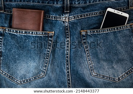 Smartphone and brown leather wallet the back pocket of blue shabby jeans hipster modern life style layout for inserting text