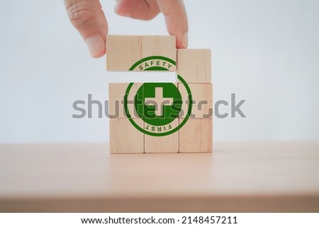 senior's hand completed green safety first sign on wooden cube blocks with copy space, work safety, caution work hazards, danger surveillance, zero accident concept. Safety banner 