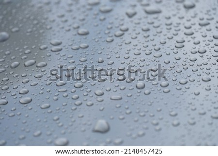 Raindrops on black hood of car closeup