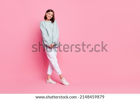 Full length photo of pretty milennial lady stand wear hoodie pants footwear isolated on pink background