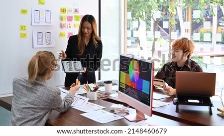Female website designer showing user interface design on digital tablet to creative team at office presentation. Royalty-Free Stock Photo #2148460679