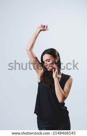 Happy woman with wireless headphones in her ears. Woman listening to music in glossy wireless headphones and rejoicing