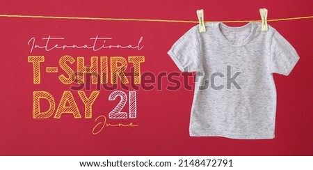 Baby t-shirt hanging on rope against color background. International T-Shirt Day