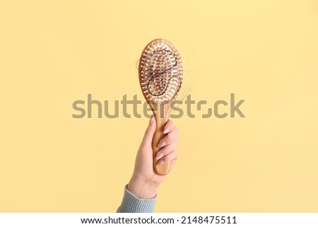 Woman holding brush with fallen down brunette hair on yellow background Royalty-Free Stock Photo #2148475511