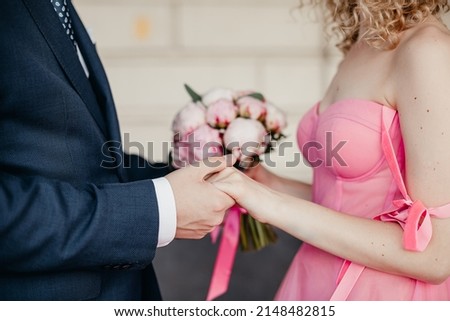 bride and groom holding hands with peony wedding bouquet