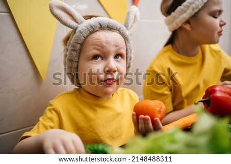 children in rabbit ears eat vegetables Easter. High quality photo