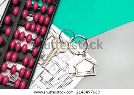 The concept of mortgage and rental housing and real estate. Mortgage credit lending. Metal keychain in the shape of a house with a key and old scores on the plan of the house. Buying a house