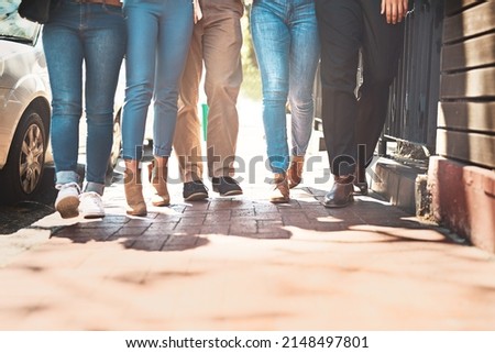 Lets take a stroll down the street guys. Low angle shot of a group of unrecognizable people walking together down a street outside during the day. Royalty-Free Stock Photo #2148497801
