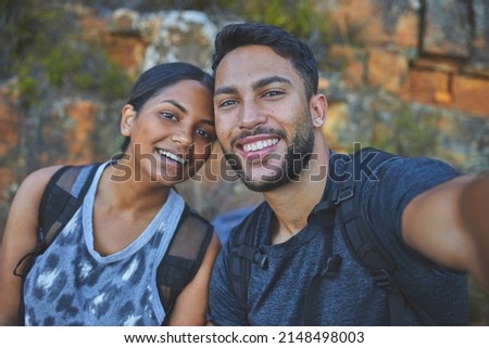 I want to remember this forever. Shot of a young couple taking photos while out on a hike in a mountain range outside.