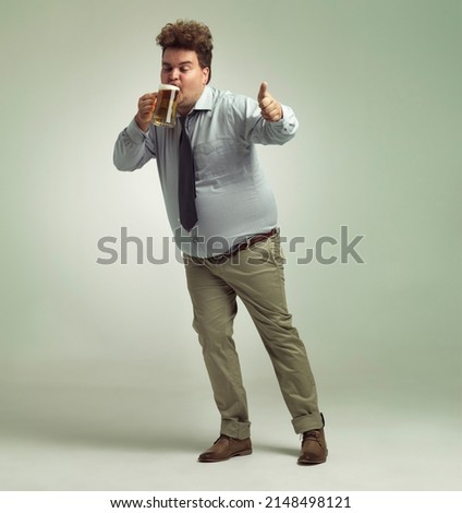 This beer is great. Shot of an overweight man giving thumbs up while drinking a pint of beer. Royalty-Free Stock Photo #2148498121