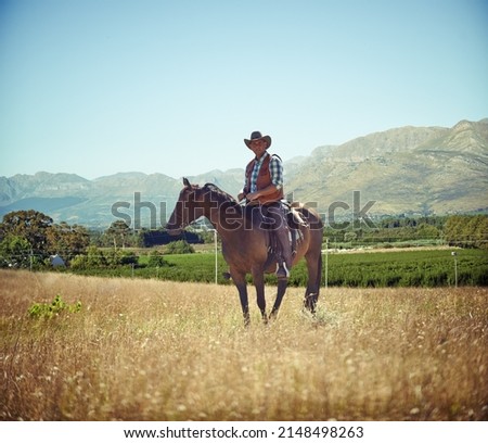 Yeeha. Full-length portrait of a mature man on a horse out in a field.