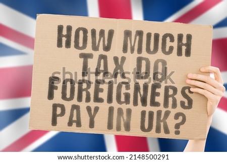 The question " How much tax do foreigners pay in UK? " on a banner in men's hands with a blurred British flag in the background. Annual. Banking. Financial. Success. Finance. Growth. Money. Offshore