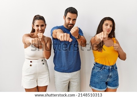 Group of young hispanic people standing over isolated background punching fist to fight, aggressive and angry attack, threat and violence 