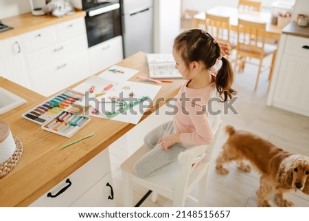 A little girl studies at home, modellng from plasticine. Little girl sculpts figures, make spring from plasticine art on paper. Art therapy for children