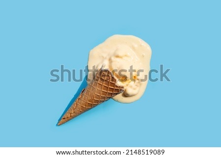 Melting ice cream balls with waffle cone on blue background. Royalty-Free Stock Photo #2148519089