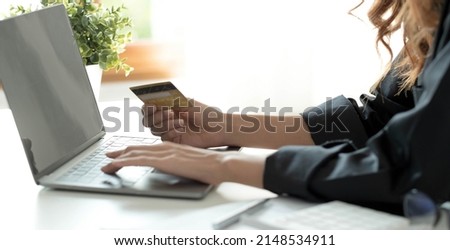 Asian woman checking online order details on computer and use the credit card information entered on the computer.
