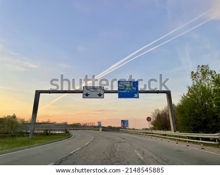Italian highway with road sign indicating Milano Malpensa airport at sunrise. High quality photo