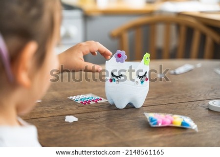 Caucasian preschool girl doing crafts with plastic bottle and paints. Recycle upcycling waste. Sustainable lifestyle Royalty-Free Stock Photo #2148561165