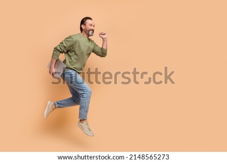 Full body photo of excited sporty man look empty space hurry rush isolated on beige color background Royalty-Free Stock Photo #2148565273