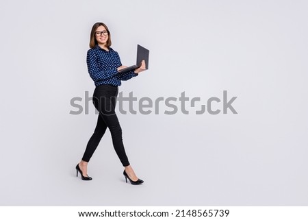 Full body profile portrait of pretty positive girl hold wireless netbook walking isolated on white color background