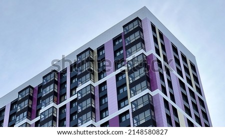 The facade of the building in purple,geometric patterns from windows and balconies, the colored wall of a modern multi-storey residential building, the abstract texture of the facade of the house Royalty-Free Stock Photo #2148580827