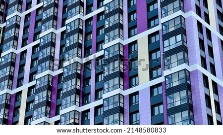 The facade of the building in purple,geometric patterns from windows and balconies, the colored wall of a modern multi-storey residential building, the abstract texture of the facade of the house Royalty-Free Stock Photo #2148580833