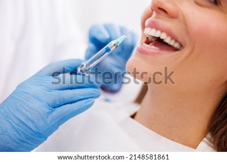 Detail of dentist applying local anesthetic to patient for numbing the pain before procedure. Focus on the drop on the top of the needle