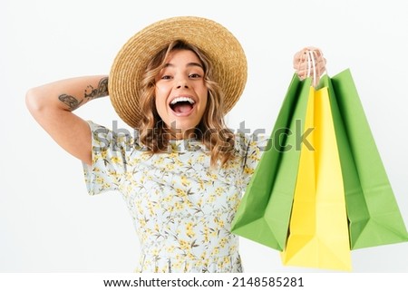 Joyful young blonde woman laughing and shouting while holding shopping bags in her hand, white background
