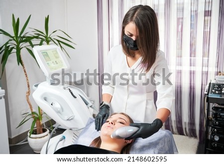 Side view of young cute woman receiving professional peeling with special modern cosmetology machine. Concept of procedure for skin in professional beauty salon. Royalty-Free Stock Photo #2148602595